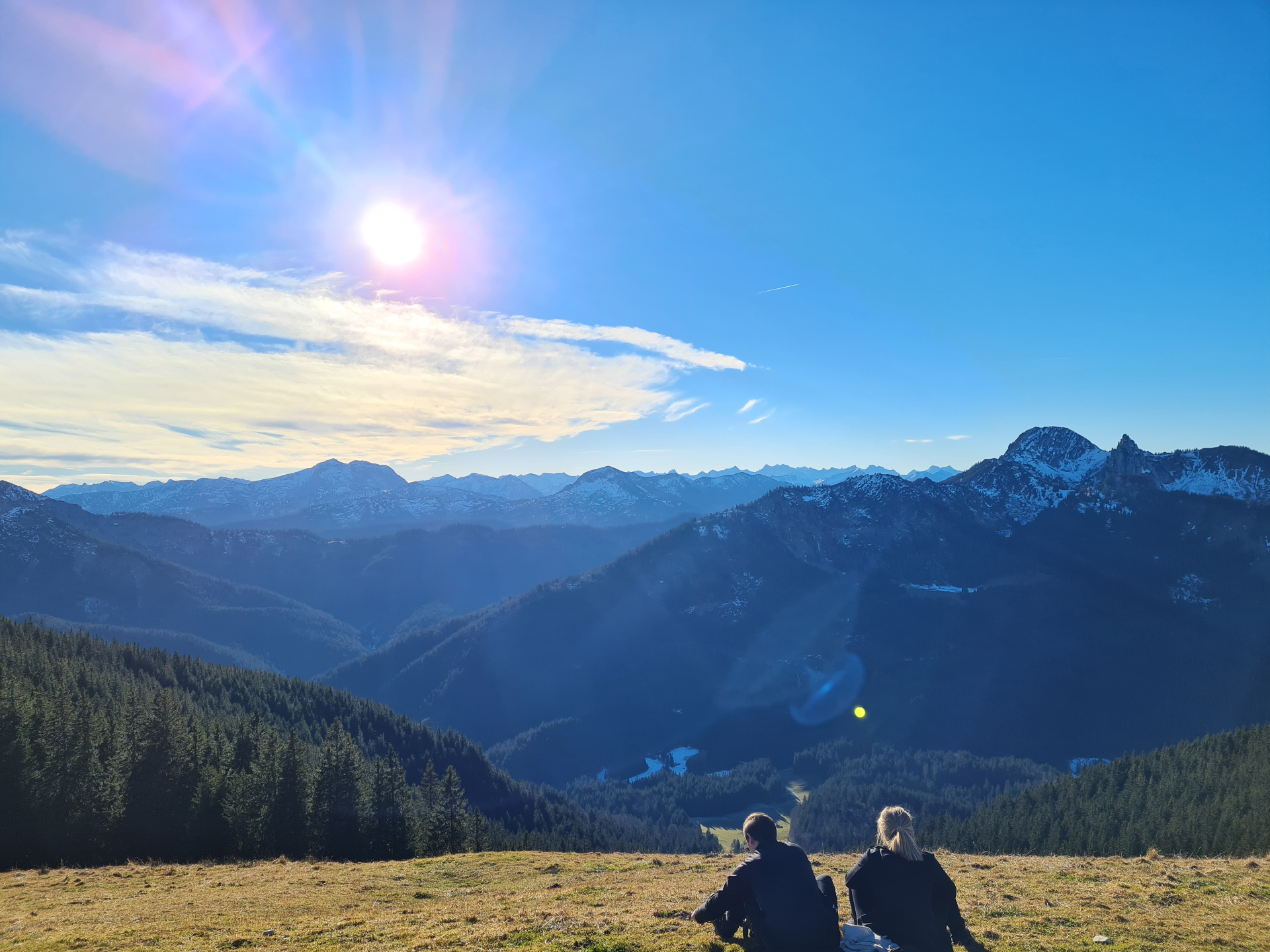 Zwei Personen blicken auf die bayerischen Alpen bei Sonnenuntergang